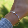 Woman wearing a Newport gold bracelet featuring 4 mm gemstones and 1/4” flat letter-engraved discs