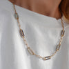 Woman wearing a 14k gold Adelaide paperclip chain pavé necklace featuring gemstone-encrusted links