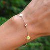 Woman's hand with a 14k gold Classic bracelet featuring one birthstone and two 1/4” flat discs engraved with letters H & A
