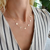 Woman wearing a 14k yellow gold cable chain necklace featuring seven 1/4” flat discs engraved with letters, spelling WGDNFCR