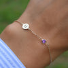 Woman wearing a 14k yellow gold Classic bracelet featuring one amethyst and one 1/4” flat disc engraved with the letter H
