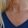 Woman wearing layered necklaces including a Rosecliff bar necklace with eleven 2 mm peridots prong set in solid 14k gold
