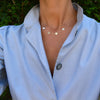 Woman wearing a 14k yellow gold cable chain necklace featuring four 1/4” flat discs engraved with the letters VDWA
