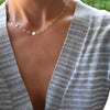 Woman wearing a Gold Newport necklace featuring 4 mm gemstones and three 1/4” flat letter-engraved discs