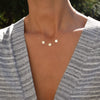 Woman wearing a 14k yellow gold cable chain necklace featuring three 1/4” flat engraved letter discs, spelling M-heart-M