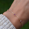 Woman with a Bayberry cable chain birthstone bracelet featuring three 4 mm briolette pink tourmalines bezel set in 14k gold