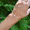 Woman wearing a 14k yellow gold cable chain bracelet featuring 1/4” flat discs engraved with letters
