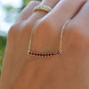 Woman's hand holding a Rosecliff bar necklace with eleven 2 mm faceted round cut garnets prong set in solid 14k yellow gold