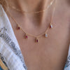 Woman wearing a Providence 5 Ruby drop necklace with petite baguette cut stones set in 14k yellow gold