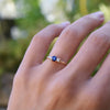 Woman wearing a Greenwich ring featuring one 4 mm faceted round cut sapphire and one 2.1 mm diamond prong set in 14k gold