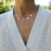 Woman wearing a 14k yellow gold cable chain necklace featuring five 1/4” flat letter-engraved discs