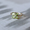 Greenwich ring featuring four 4 mm faceted round cut peridots and one 2.1 mm diamond prong set in 14k yellow gold