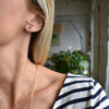 Woman wearing a Birthstone Stud Earring featuring a 4 mm briolette cut Ruby bezel set in 14k gold