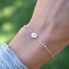 Woman with a 14k gold Classic bracelet featuring two birthstones and one 1/4” flat disc, engraved with a four leaf clover