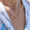 Woman wearing a Providence 5 Sapphire drop necklace with petite baguette cut stones set in 14k yellow gold
