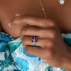 Woman wearing a Greenwich ring featuring four 4 mm faceted round cut sapphires and one 2.1 mm diamond prong set in 14k gold