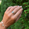 Woman wearing a Greenwich ring featuring four 4 mm round Nantucket blue topaz and one 2.1 mm diamond prong set in 14k gold