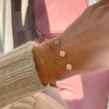 Woman wearing bracelets including a 14k yellow gold bracelet featuring three 1/4” flat engraved letter discs, spelling XOX