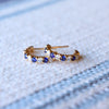 A pair of Rosecliff huggie earrings in 14k gold each featuring nine alternating 2mm round cut sapphires and diamonds