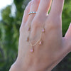 A woman's hand holding a Providence 5 Pink Tourmaline drop necklace featuring 5 petite baguette cut stones set in 14k gold