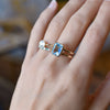 Woman's hand wearing multiple rings including a Warren ring in 14k gold featuring one emerald cut Nantucket blue topaz