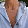 Woman wearing a 14k yellow gold Classic necklace featuring four garnets and one 1/4” flat disc engraved with the letter H