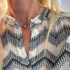 Woman wearing two gold necklaces including a Greenwich necklace featuring five 4 mm pink tourmalines and one 2.1 mm diamond