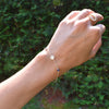 Woman wearing a 14k yellow gold Classic bracelet featuring two birthstones and 1/4” flat letter-engraved discs