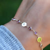 Woman wearing a Newport 14k gold bracelet featuring 4 mm gemstones and 1/4” flat letter-engraved discs