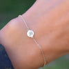 Woman with a 14k yellow gold Classic cable chain bracelet featuring one 1/4” flat disc engraved with a four leaf clover