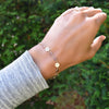 Woman with a Newport 14k gold bracelet featuring 4 mm gemstones and 1/4” flat letter-engraved discs