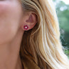 Woman wearing a 14k yellow gold Greenwich 5 Birthstone earring featuring five 4 mm rubies and one 2.1 mm diamond