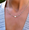 Woman wearing a 14k gold Newport necklace featuring 4 mm gemstones and a 1/4” flat letter-engraved disc