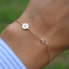 Woman wearing a 14k yellow gold Classic bracelet featuring one white topaz and one 1/4” flat disc engraved with the letter H
