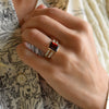 Woman's hand wearing a Warren ring in 14k gold with accent diamonds featuring one 10 x 8 mm emerald cut bezel set garnet