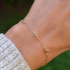 Woman with a Bayberry cable chain birthstone bracelet featuring three 4 mm briolette peridots bezel set in 14k yellow gold