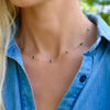 Woman wearing a Bayberry 11 Birthstone necklace featuring 4 mm briolette emeralds bezel set in 14k gold