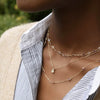 Woman wearing layered necklaces including a Greenwich necklace featuring one 4 mm round cut opal and one 2.1 mm diamond