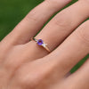 Woman wearing a Greenwich ring featuring one 4 mm faceted round cut amethyst and one 2.1 mm diamond prong set in 14k gold