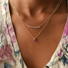 Woman wearing two gold necklaces including a Rosecliff bar necklace with eleven alternating 2 mm amethysts and diamonds