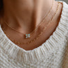 Woman with a Greenwich cable chain necklace featuring four 4 mm round opals and one 2.1 mm diamond bezel set in 14k gold