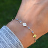 Woman wearing a Newport 14k gold bracelet featuring 4 mm gemstones and 1/4” flat letter-engraved discs