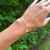 Woman wearing a 14k yellow gold Classic bracelet featuring one birthstone and two 1/4” flat discs engraved with letters H & A