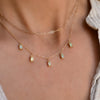 Woman wearing a Providence 5 Peridot drop necklace with petite baguette cut stones set in 14k yellow gold