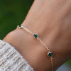 Woman with a Bayberry cable chain birthstone bracelet featuring three 4 mm briolette emeralds bezel set in 14k gold