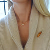 Woman wearing a 14k yellow gold 1.17 mm cable chain necklace featuring one 1/4” flat disc engraved with a heart