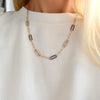 Woman with a 14k gold Adelaide paperclip chain pavé necklace featuring gemstone-encrusted links
