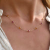 Woman wearing a Sunset necklace featuring seven alternating 4 mm Pink Tourmalines and Citrines bezel set in 14k yellow gold