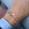 Woman wearing a 14k gold Solidarity bracelet featuring two birthstones and one 1/4” flat disc engraved with a sunflower