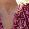 Woman wearing a Rosecliff bar necklace featuring eleven 2 mm faceted round cut aquamarines prong set in 14k yellow gold